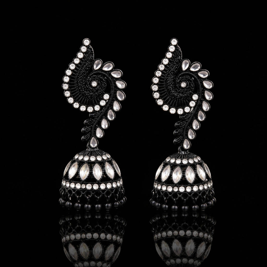 A pair of ornate black and silver jhumka earrings with intricate paisley and floral motifs, displayed on a reflective black surface.