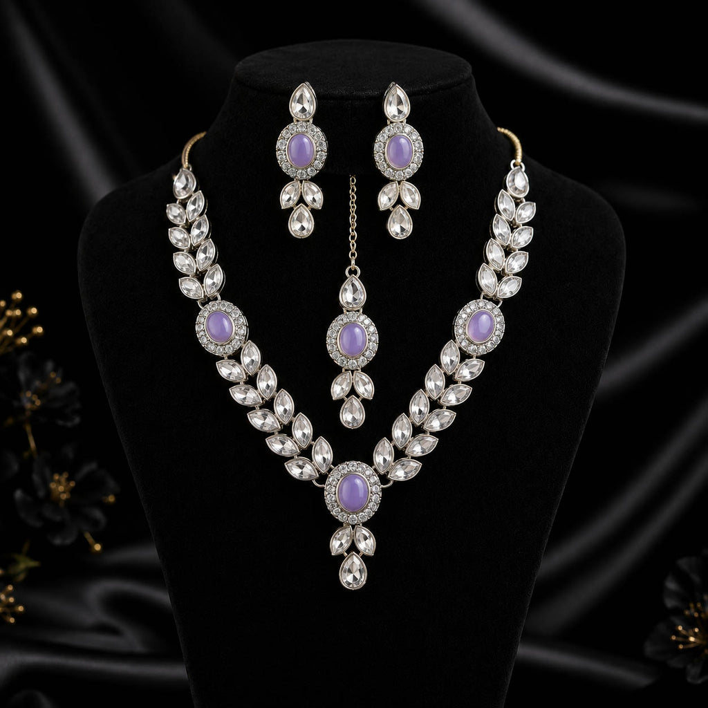 A silver-tone jewelry set featuring a necklace, matching earrings, and a choker pendant, decorated with clear crystals and lavender purple oval stones, displayed on a black velvet stand.