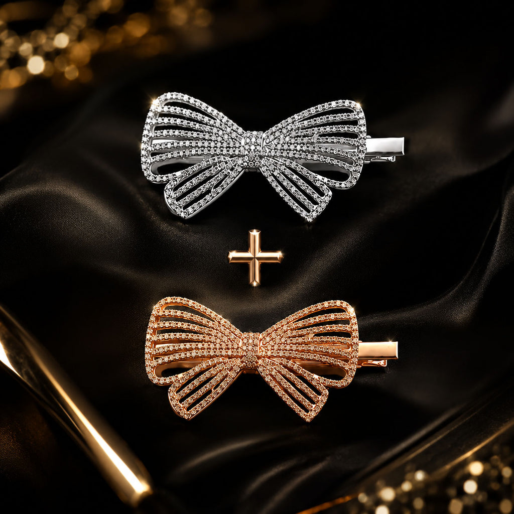 Two bow-shaped hair claw clips, one silver and one rose gold, both paved with clear rhinestones, displayed on a black satin fabric background with a small gold cross accent.