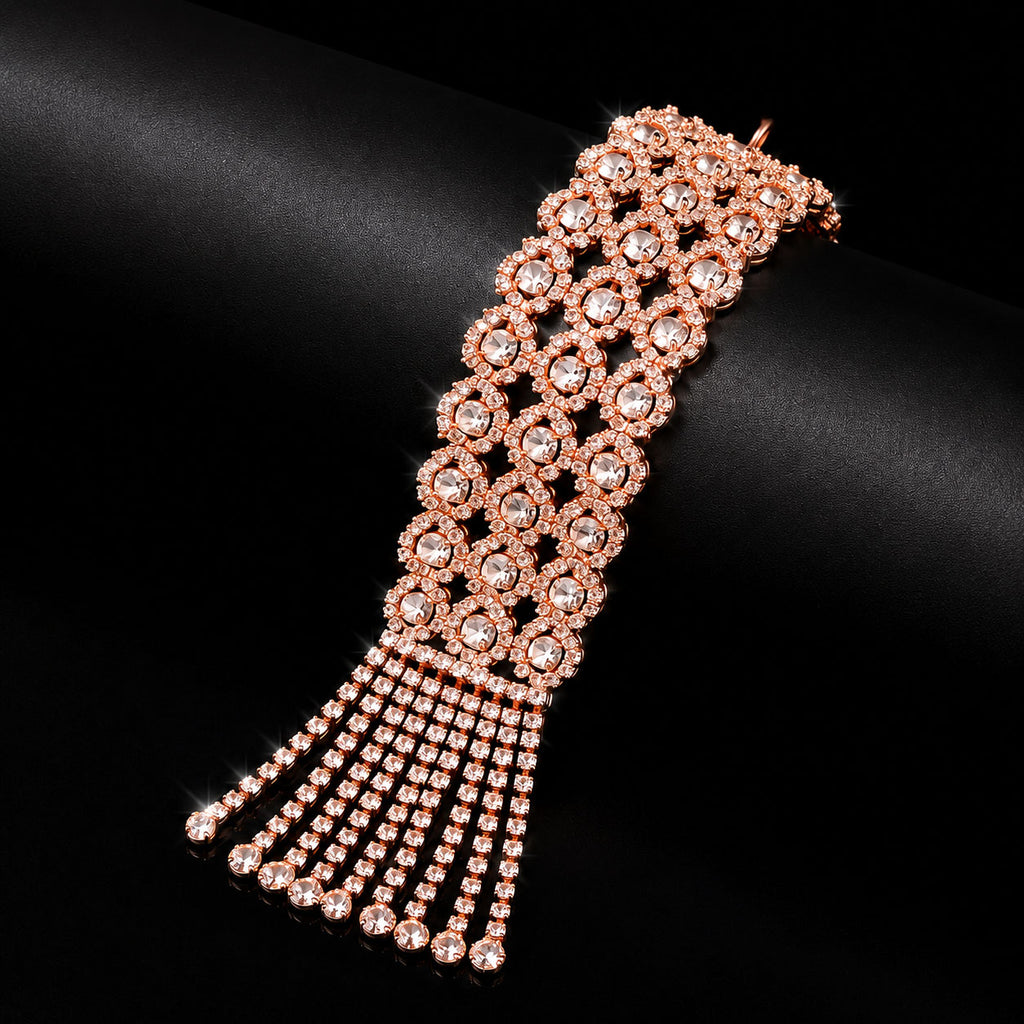 A rose gold choker-style bracelet with a wide floral pattern and dangling fringe, embellished with clear rhinestones, displayed on a black satin surface.