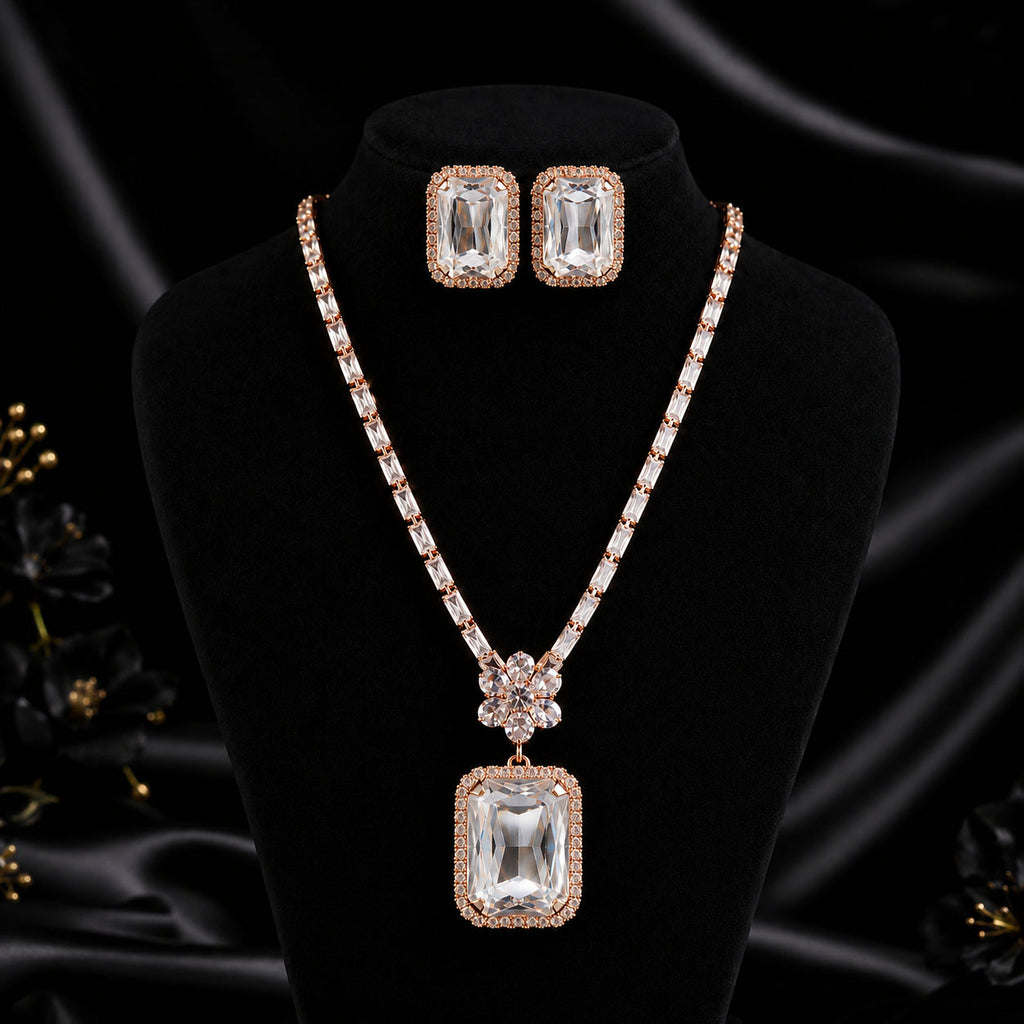 Rose gold jewelry set featuring a rectangular pendant necklace and matching stud earrings, displayed on a black velvet mannequin bust against a black satin background.