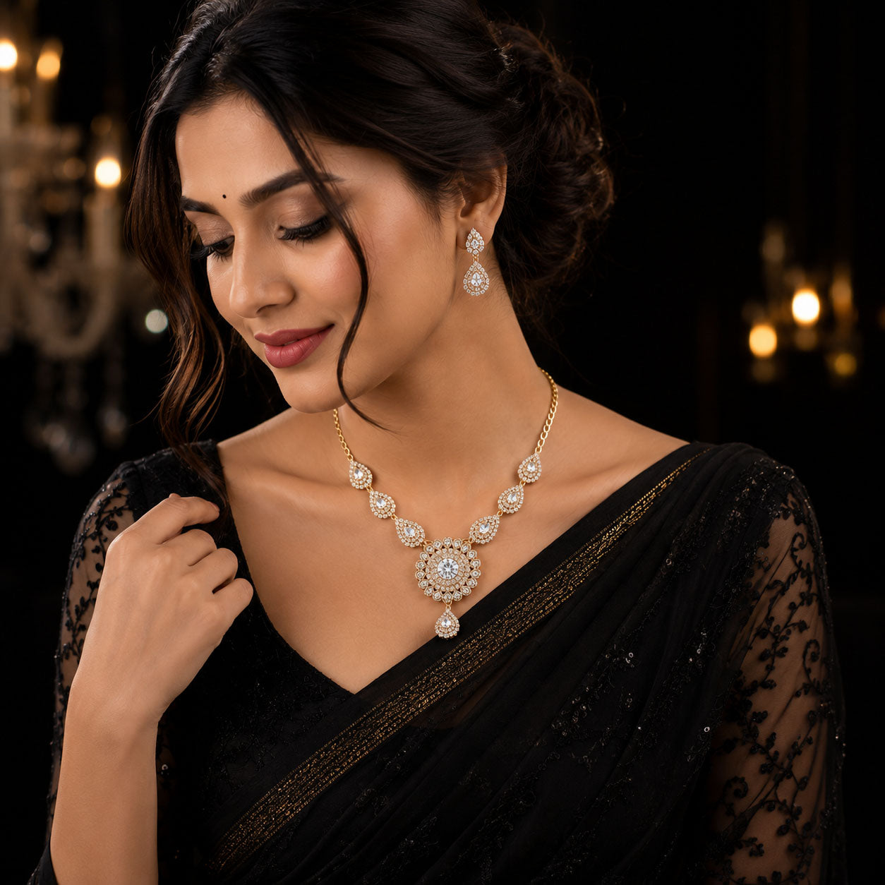 A woman wearing a black embroidered saree and jewelry, featuring a gold and white stone necklace with matching drop earrings, set against a dark, softly lit background.