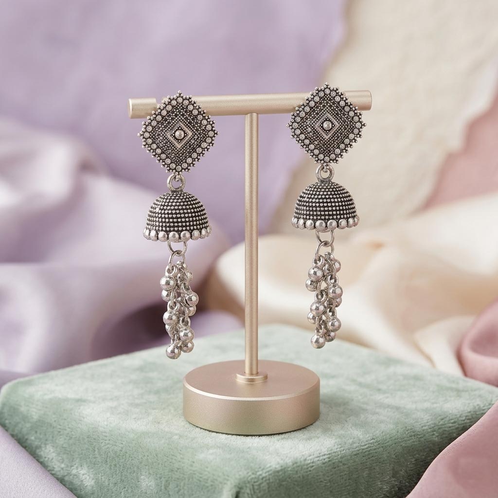 Pair of silver earrings on a display stand with a soft background