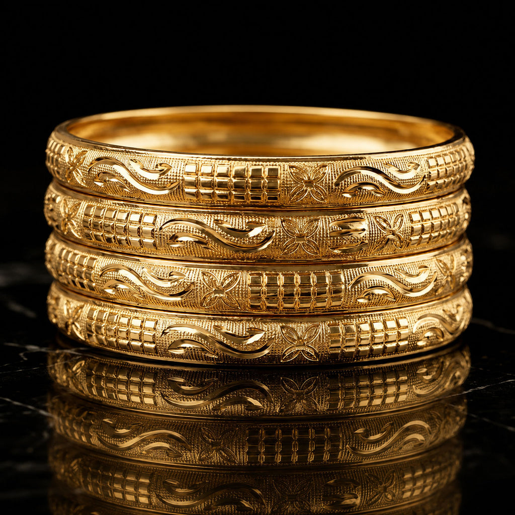 Four stacked gold bangles with intricate engraved patterns, displayed on a reflective black surface against a black background.