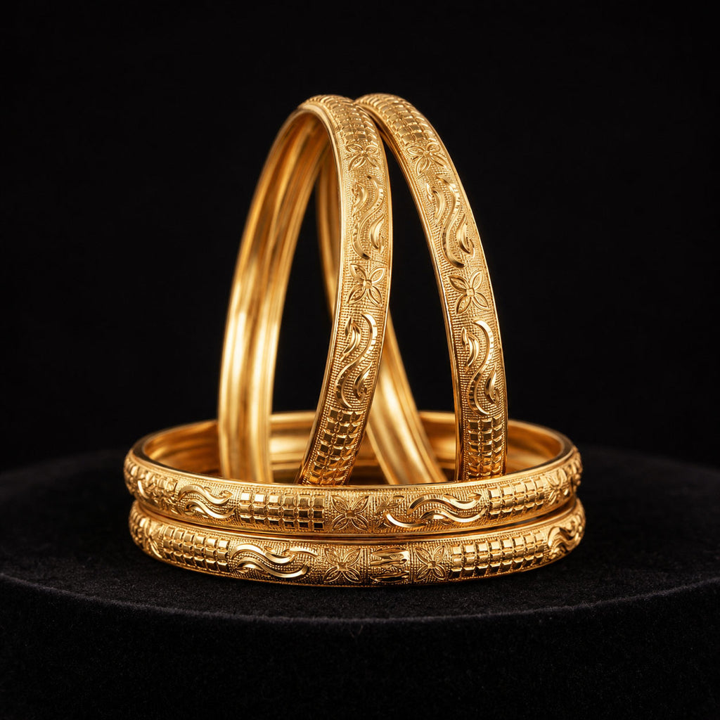 Three ornate gold bangles with intricate floral and geometric engravings, stacked on a black surface against a black background.