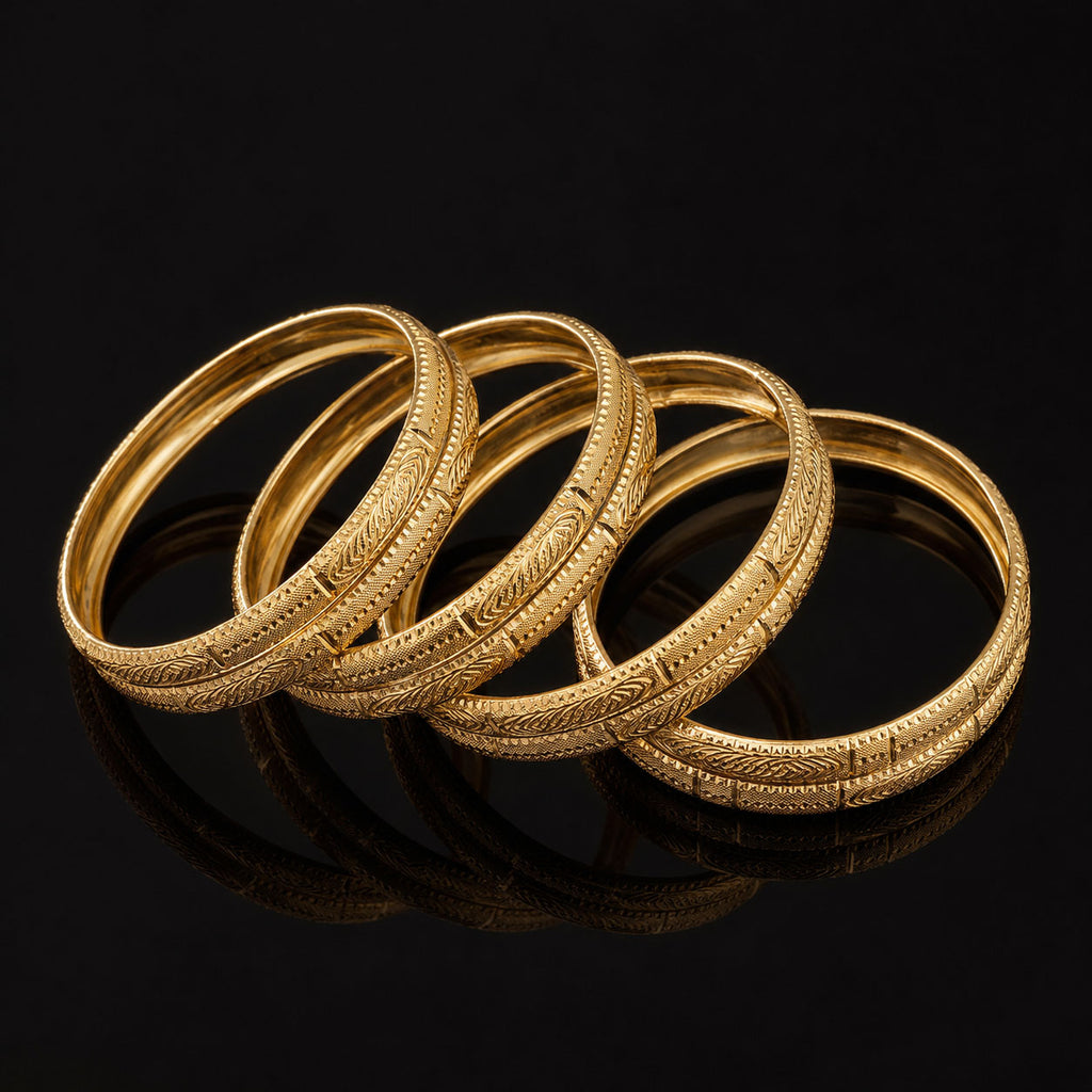 Four gold bangles with detailed engraved patterns, arranged in an overlapping circle on a reflective black surface.